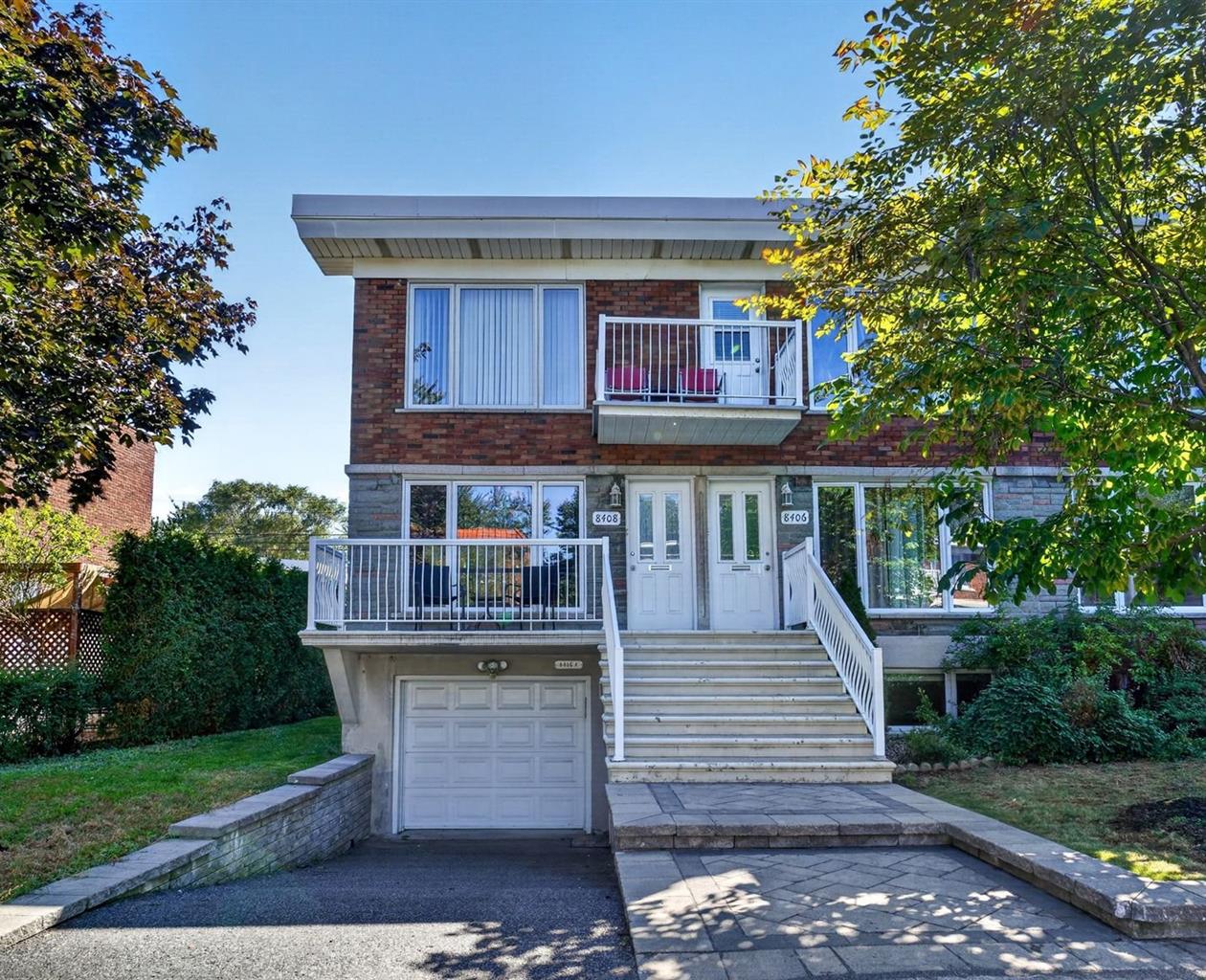 Duplex à Anjou avec façade en brique, balcons blancs et garage intégré